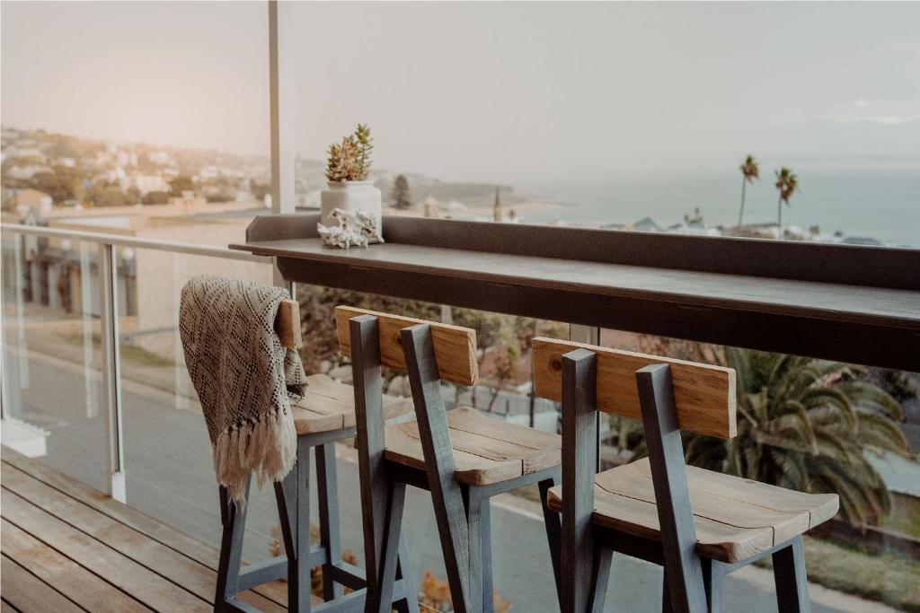 
a row of chairs sitting on top of a wooden deck at Aqua Marina Guest House in Mossel Bay
