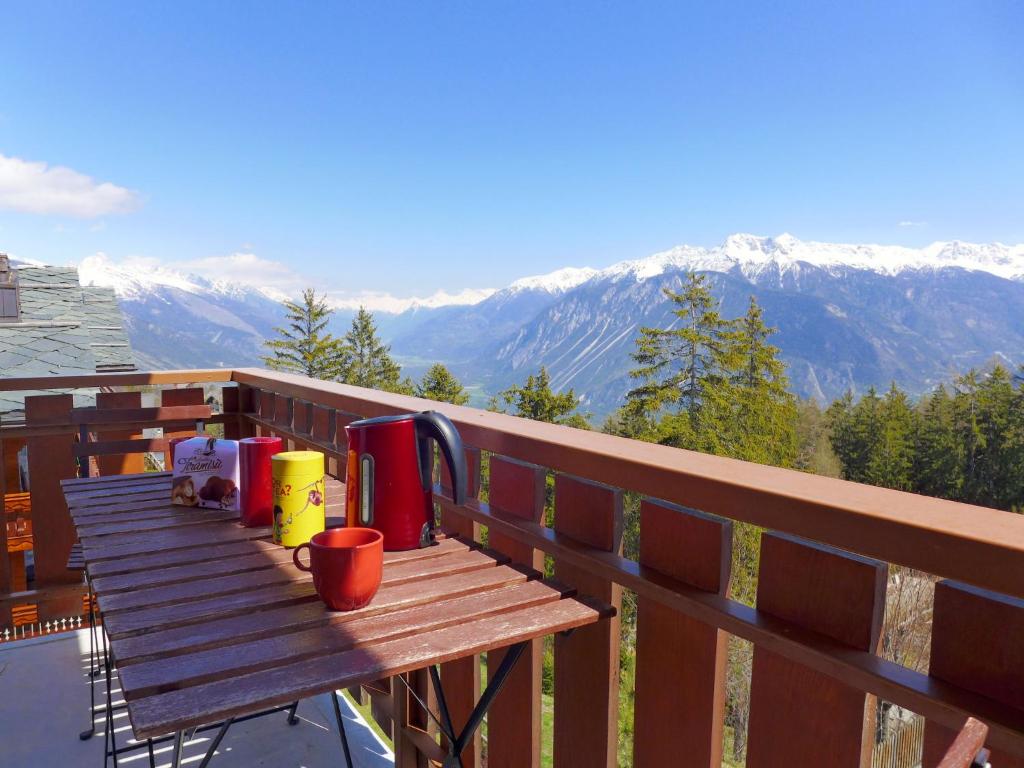 a wooden table on a balcony with a view of mountains at Apartment Andrea A 10 by Interhome in Crans-Montana