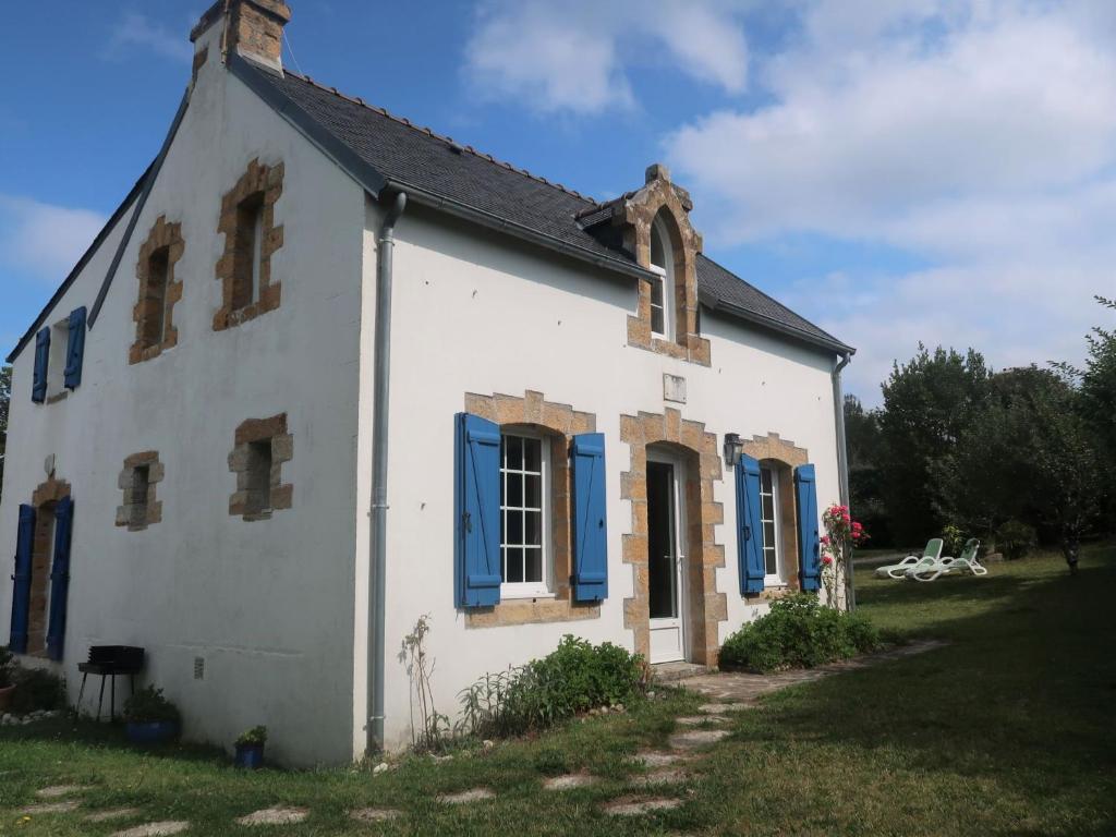 Una vieja casa blanca con persianas azules. en Holiday Home Les Sapins by Interhome, en Morgat