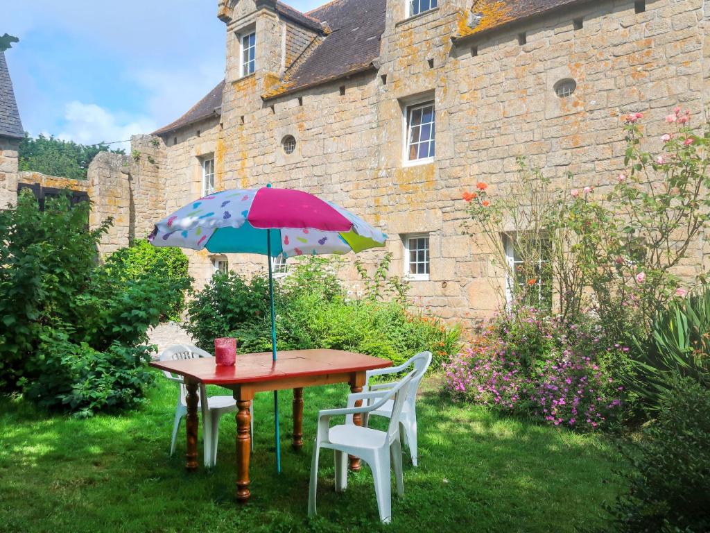 une table avec un parasol coloré sur l'herbe dans l'établissement Holiday Home Le Manoir by Interhome, à Pont-lʼAbbé