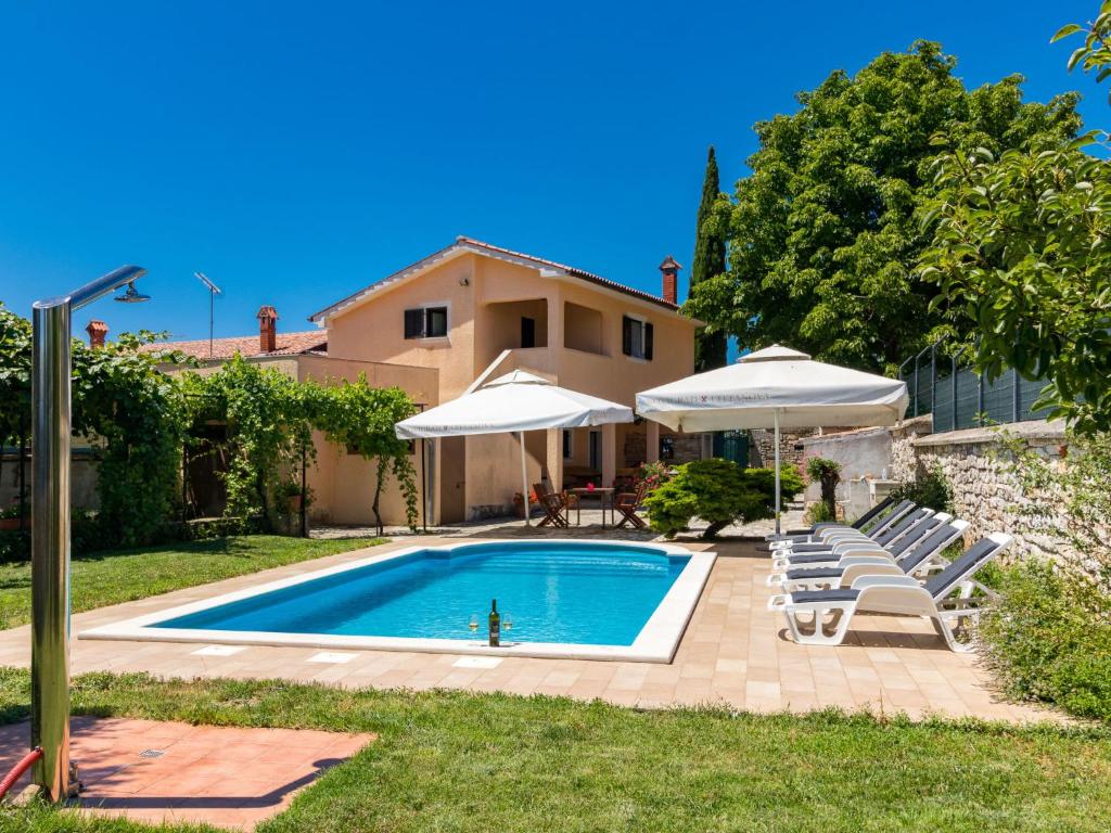 einen Pool mit Stühlen und Sonnenschirmen vor einem Haus in der Unterkunft Holiday Home Villa San Giacomo - KST416 by Interhome in Tinjan