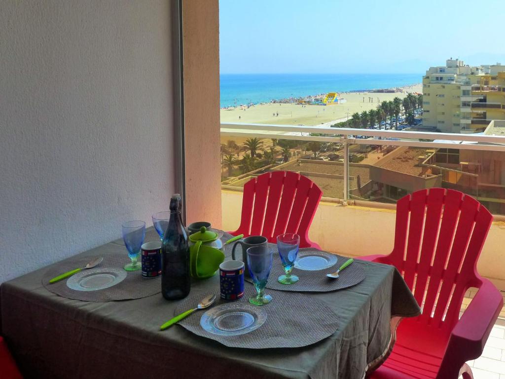a table with red chairs and a view of the beach at Apartment Soleil Bleu-8 by Interhome in Canet-en-Roussillon