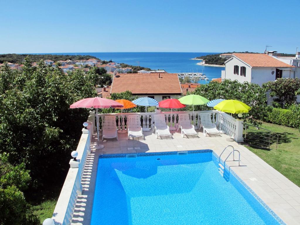 a view of a swimming pool with umbrellas and chairs at Apartment Villa Ursa - PUL320 by Interhome in Pješčana Uvala