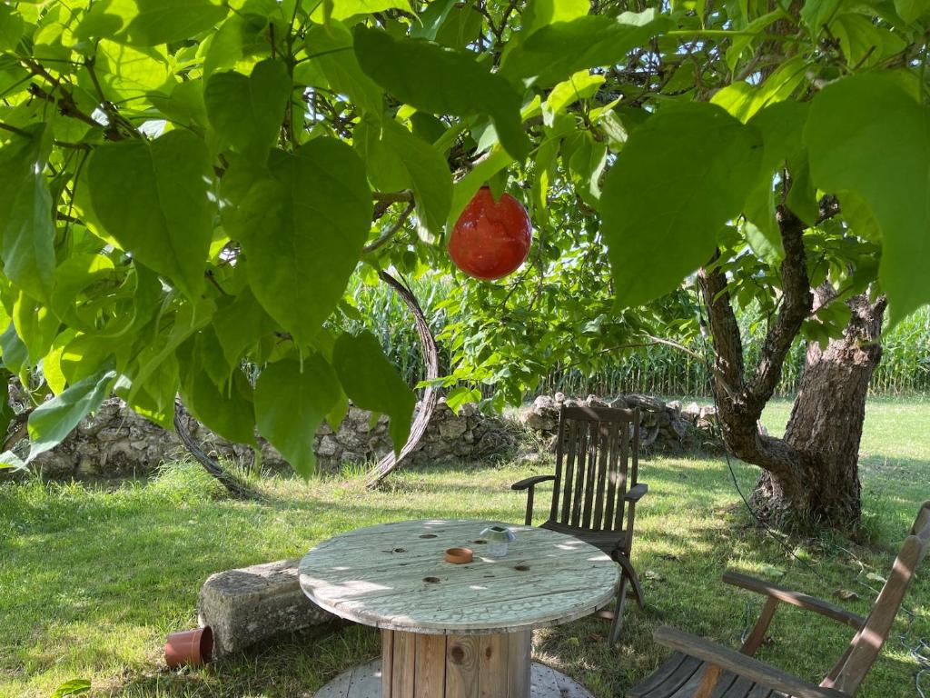 une table en bois et une chaise sous un arbre dans l'établissement In the heart of artists's house, à Espiens
