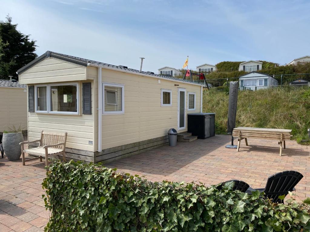 ein winziges Haus mit einem Picknicktisch und einer Bank in der Unterkunft Chalet Ibiza in de duinen van IJmuiden aan Zee in IJmuiden