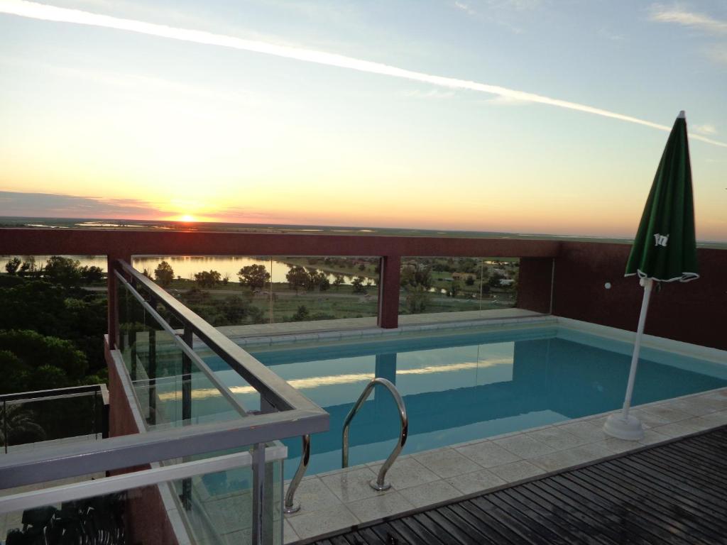a swimming pool on the roof of a building with the sunset at Rio Manso Apart Hotel in Victoria