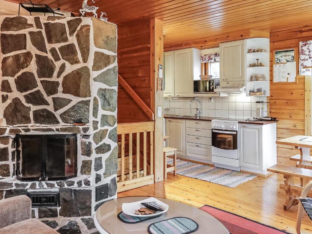 a kitchen and living room with a stone fireplace at Holiday Home Sallanrinne b by Interhome in Salla
