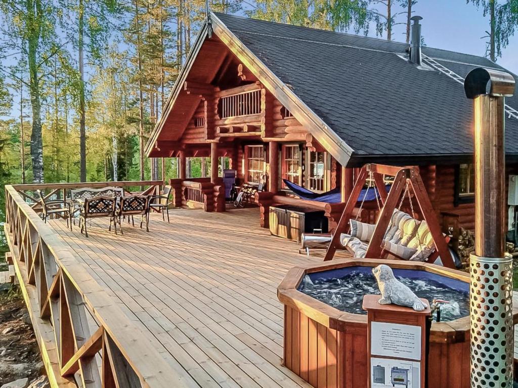 une cabane en rondins avec un bain à remous sur une terrasse en bois dans l'établissement Holiday Home Erätorsa by Interhome, à Torsansalo