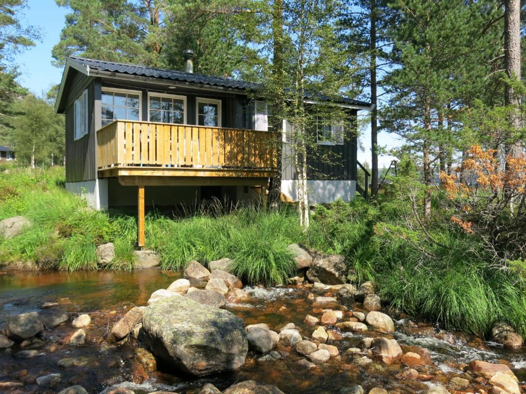 uma casa na floresta ao lado de um riacho em Chalet Sandrabu - SOW056 by Interhome em Øyuvstad