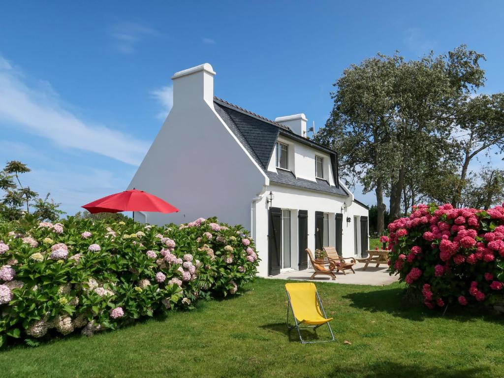ein weißes Haus mit einem roten Regenschirm und ein paar Blumen in der Unterkunft Holiday Home Ty va Zud by Interhome in Lampaul-Ploudalmézeau