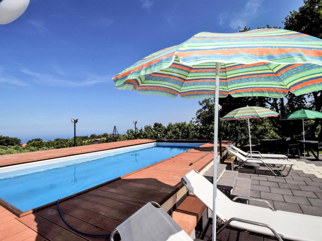 - une piscine avec des chaises et un parasol à côté de la piscine dans l'établissement Studio Serena by Interhome, à Piedimonte Etneo