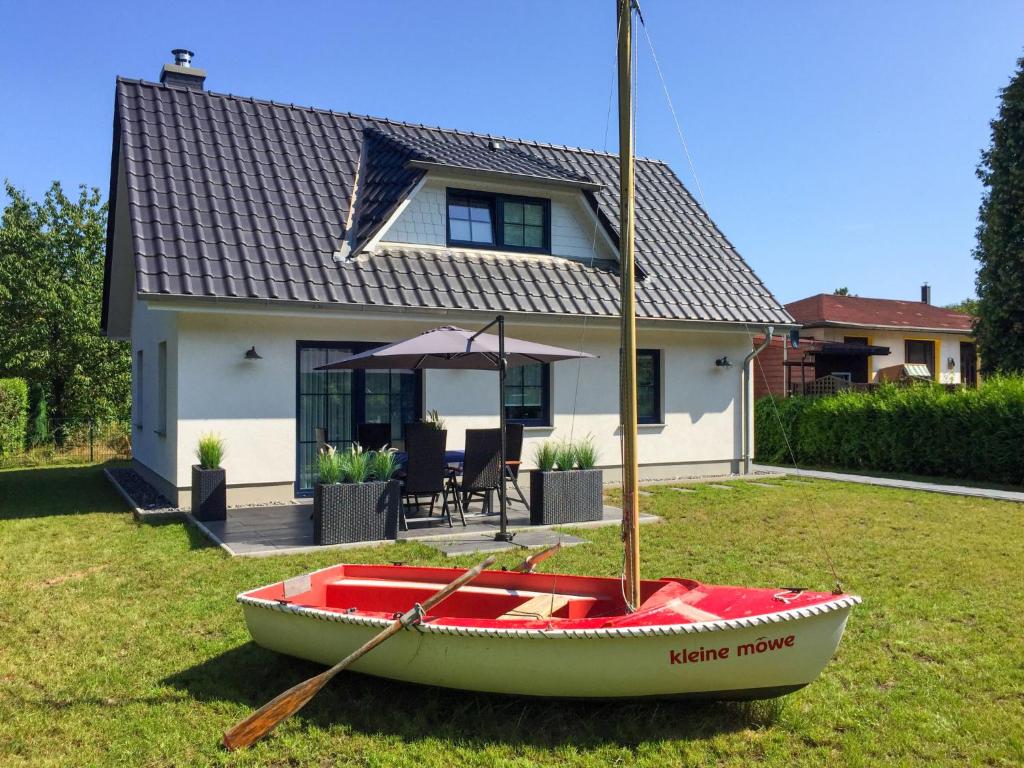 una barca seduta sull'erba di fronte a una casa di Holiday Home Kleine Möwe by Interhome a Zirkow