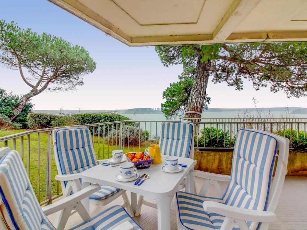 une table et des chaises blanches sur une terrasse avec vue sur l'eau dans l'établissement Apartment La Baie by Interhome, à Dinard