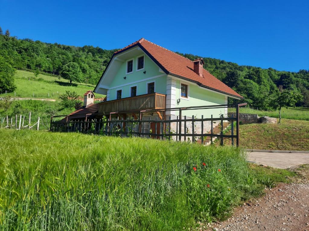 a house on top of a field with a fence at Vineyard cottage Klobčar in Semič