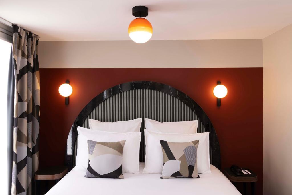 a bedroom with a large bed with white pillows at Hôtel Regina Opéra Grands Boulevards in Paris