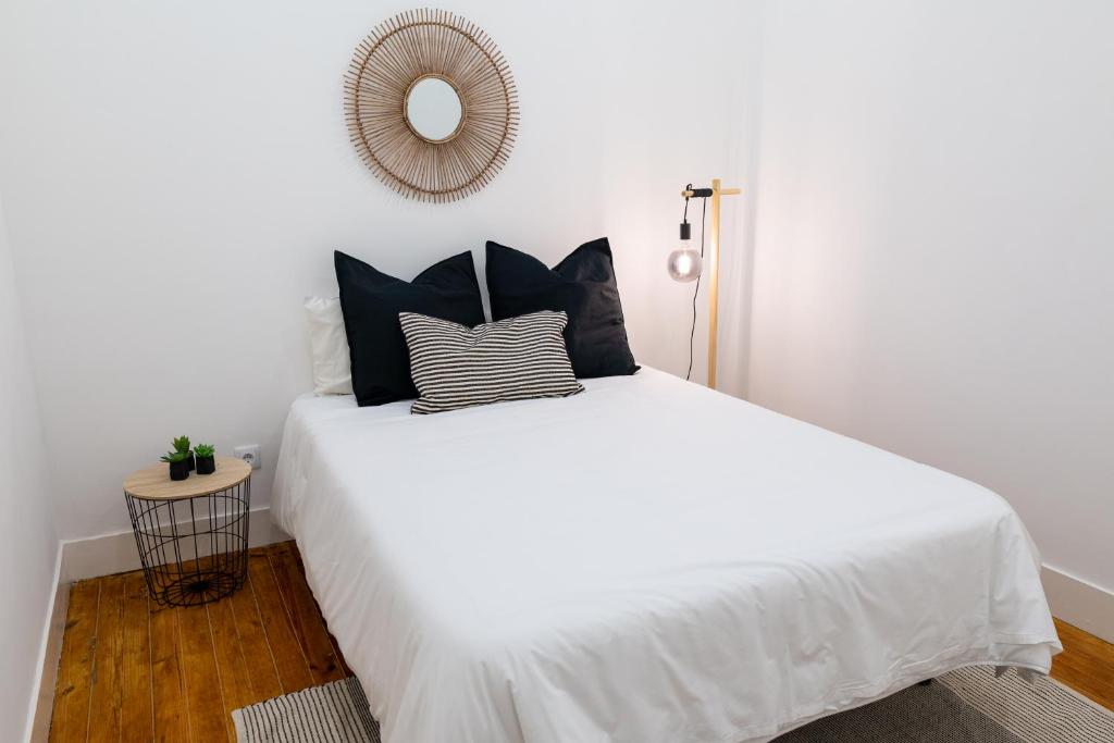 uma cama branca com almofadas pretas e um espelho em Lovely Home em Lisboa