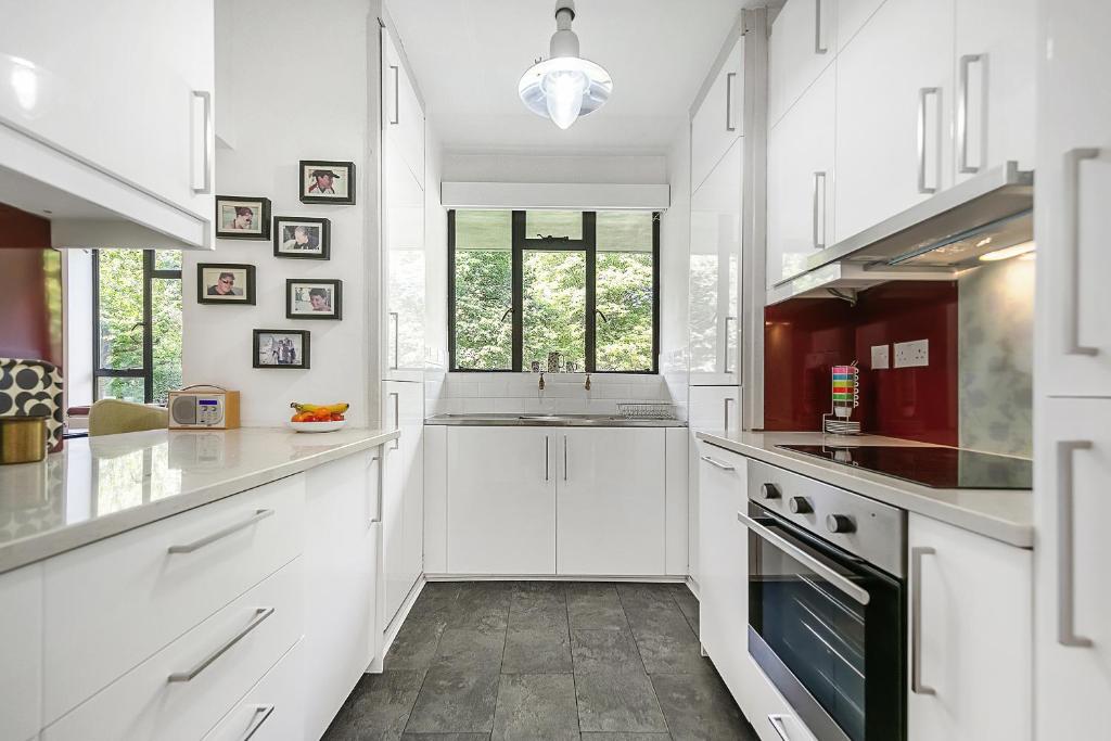 a white kitchen with white cabinets and a sink at Veeve - Thirties Icon By Sadler's Wells in London