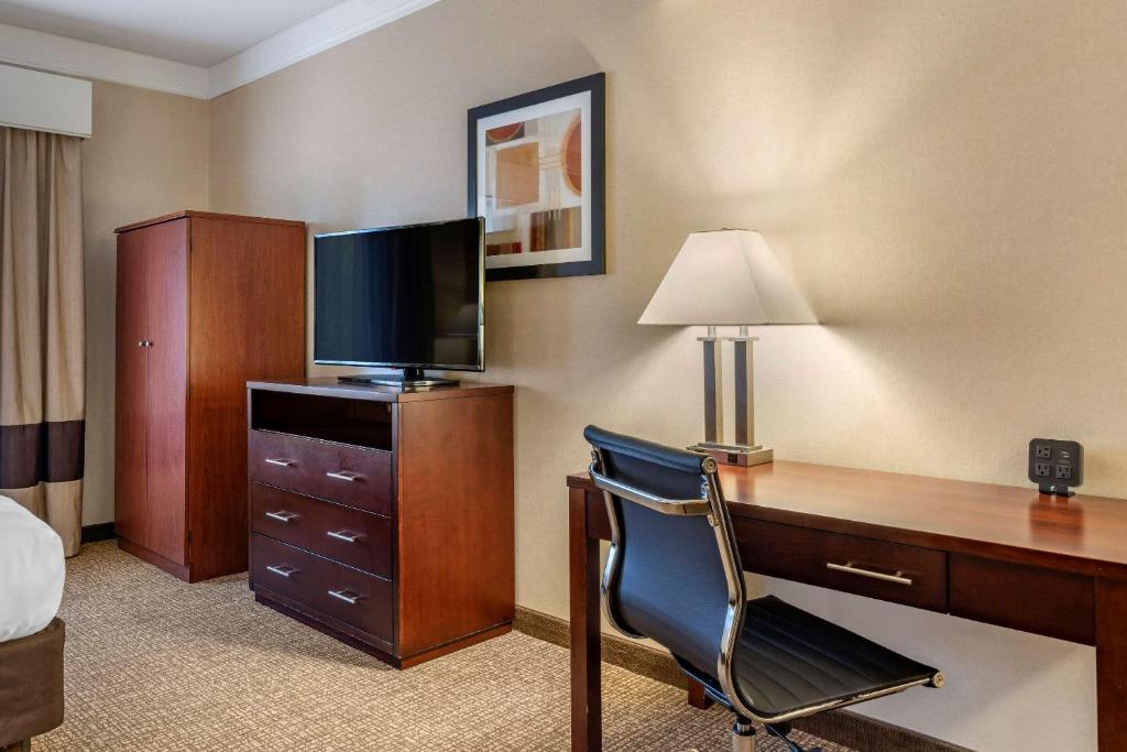 a hotel room with a desk with a television and a bed at Comfort Suites Linn County Fairground and Expo in Albany