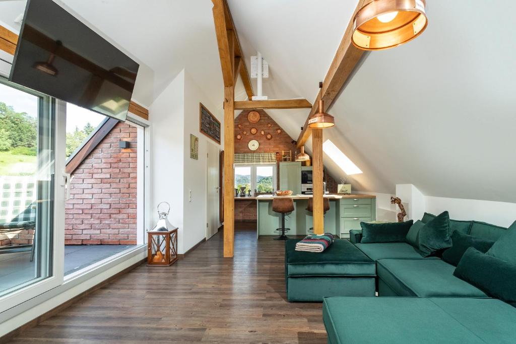 a living room with green furniture and a large window at Pine Cone Loft on Baden-Baden's Panorama Trail in Baden-Baden