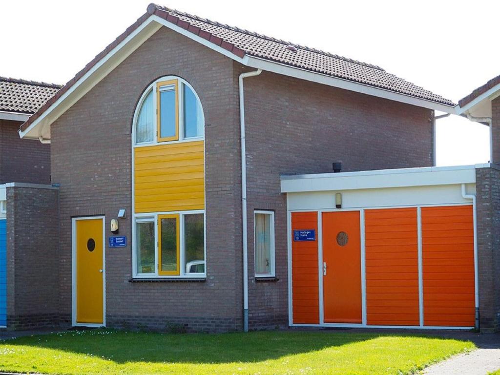 una casa con puertas de garaje de color naranja y amarillo en Semi-detached house with a dishwasher, located in Friesland, en Franeker