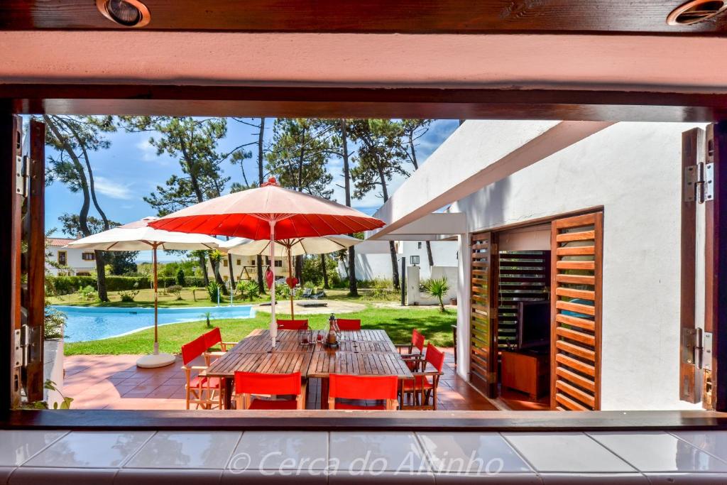 a dining room with a table and chairs and an umbrella at Cerca do Altinho in Vila Nova de Milfontes