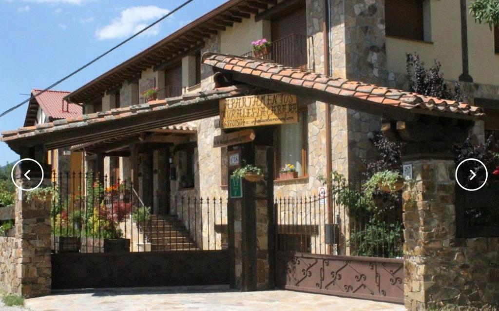 budynek z ogrodzeniem i bramą z kwiatami w obiekcie Apartamentos Rurales "La Cabaña" w mieście Rascafría
