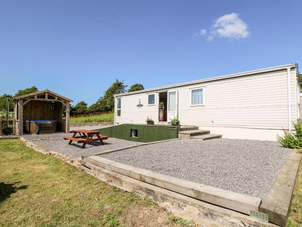 um edifício com uma mesa de piquenique e um banco em The Lodge em Llanelli