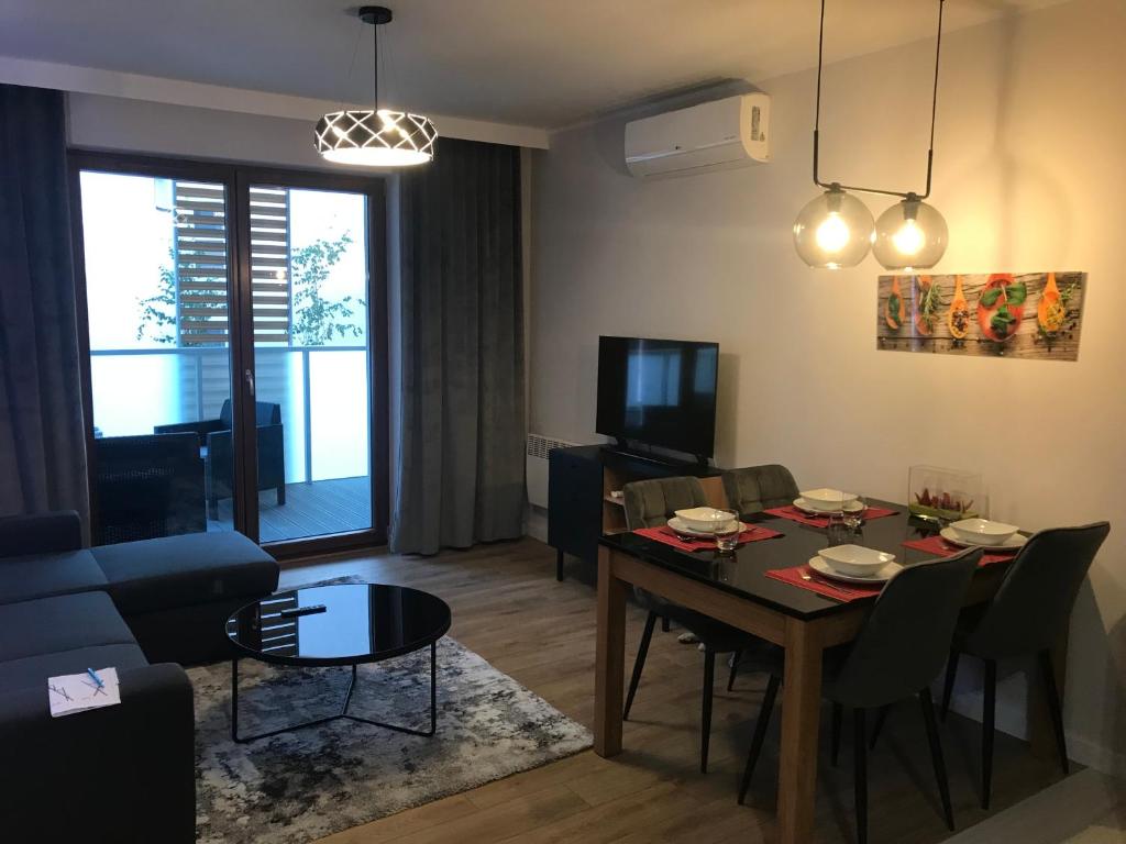 a living room with a table and a dining room at APARTAMENT D-7 W OBIEKCIE NAUTIKKA PARK in Krynica Morska