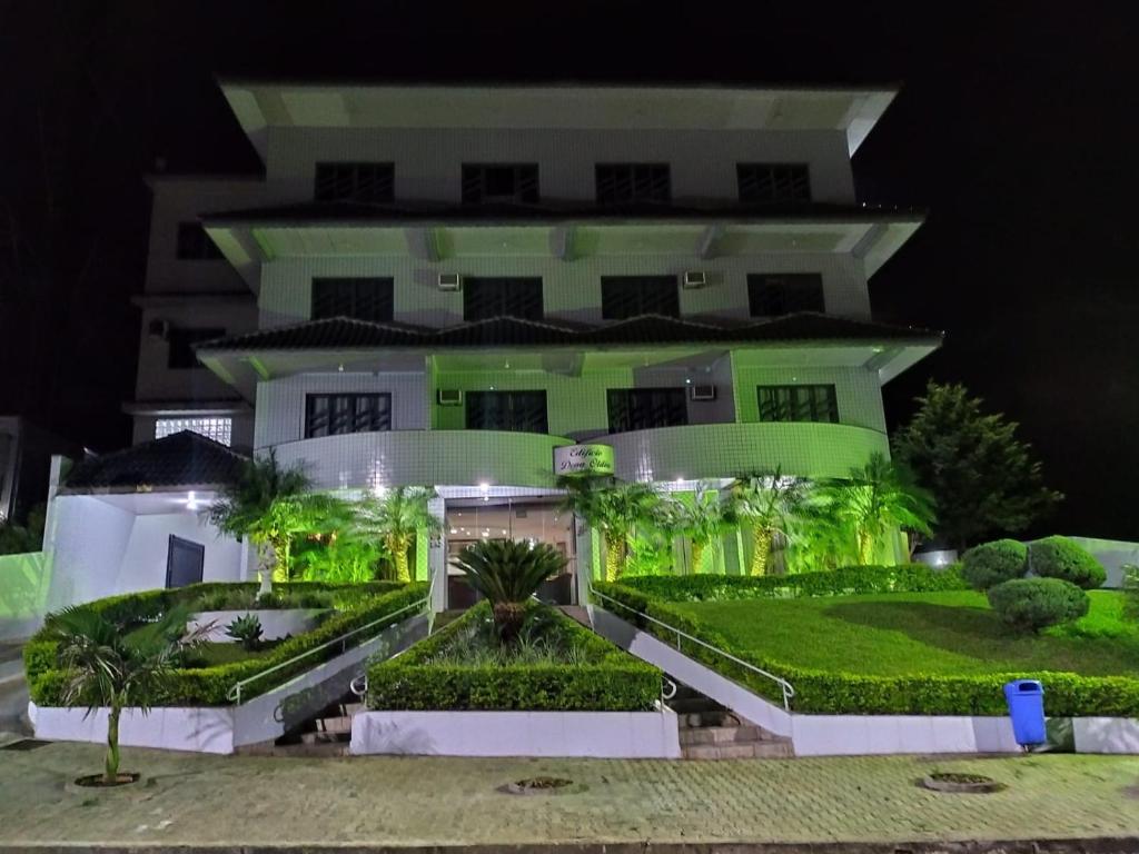uma grande casa branca com plantas verdes em frente em Elite Palace Hotel em Prudentópolis