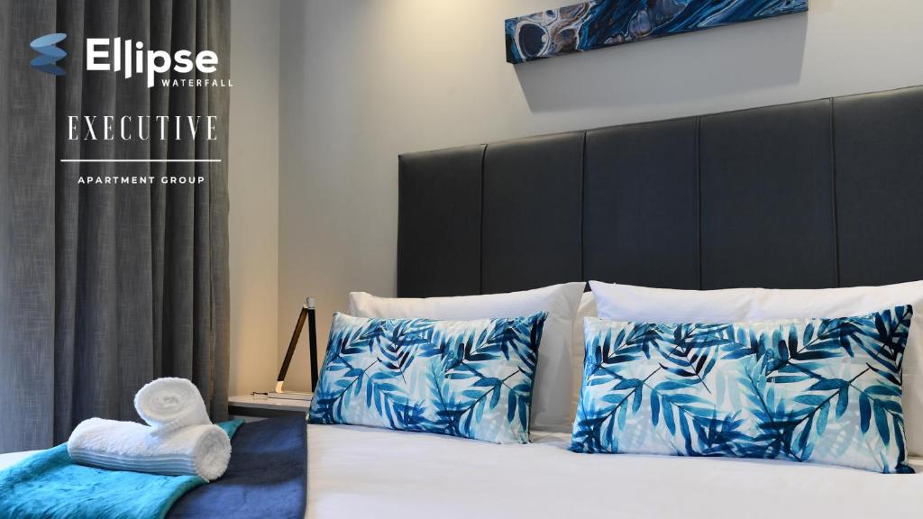 a bedroom with a bed with blue and white pillows at Ellipse Waterfall Executive Apartments in Midrand