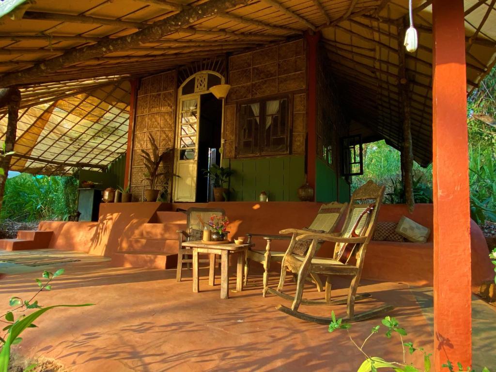 a porch of a house with chairs and a table at Khaama Kethna Eco Sustainable Village in Agonda