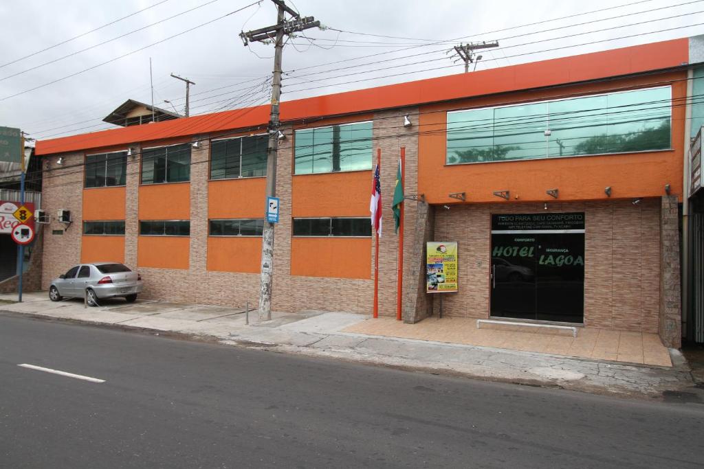 een oranje gebouw met een auto ervoor geparkeerd bij Hotel Lagoa in Manaus