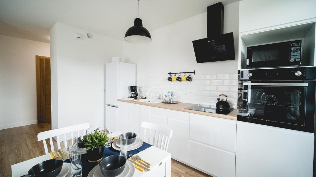 uma cozinha com armários brancos, uma mesa e um micro-ondas em Apartament Marbud przy Aquaparku Reda em Rumia