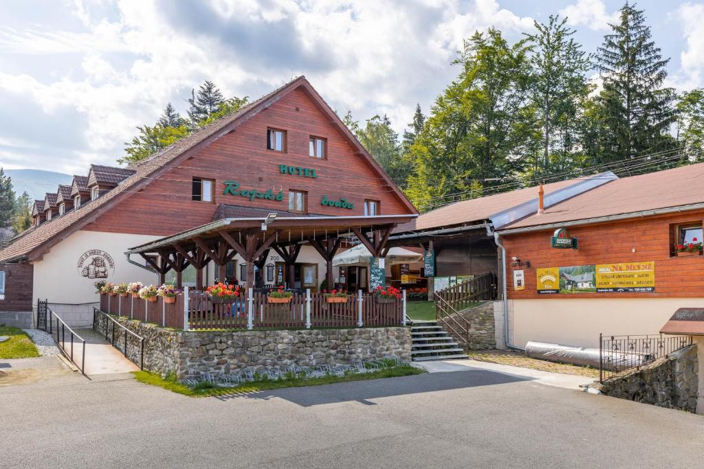 un gran edificio de madera con una valla delante en Horsky hotel Rajska bouda, en Malenovice