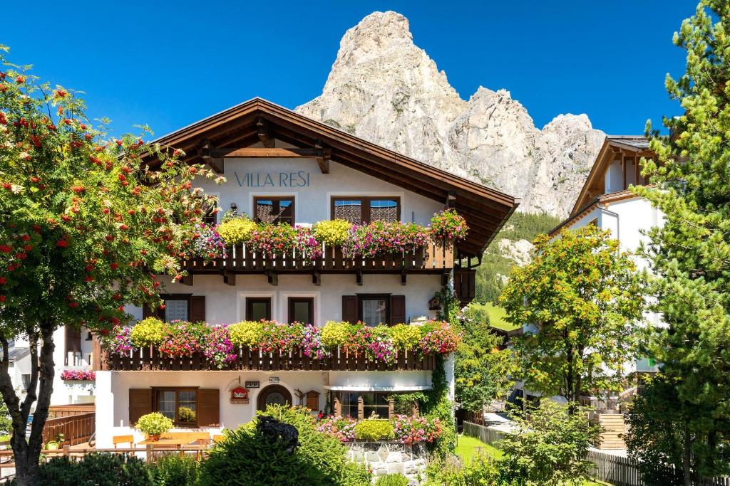 a building with flowers in front of a mountain at Villa Resi Apartments in Corvara in Badia