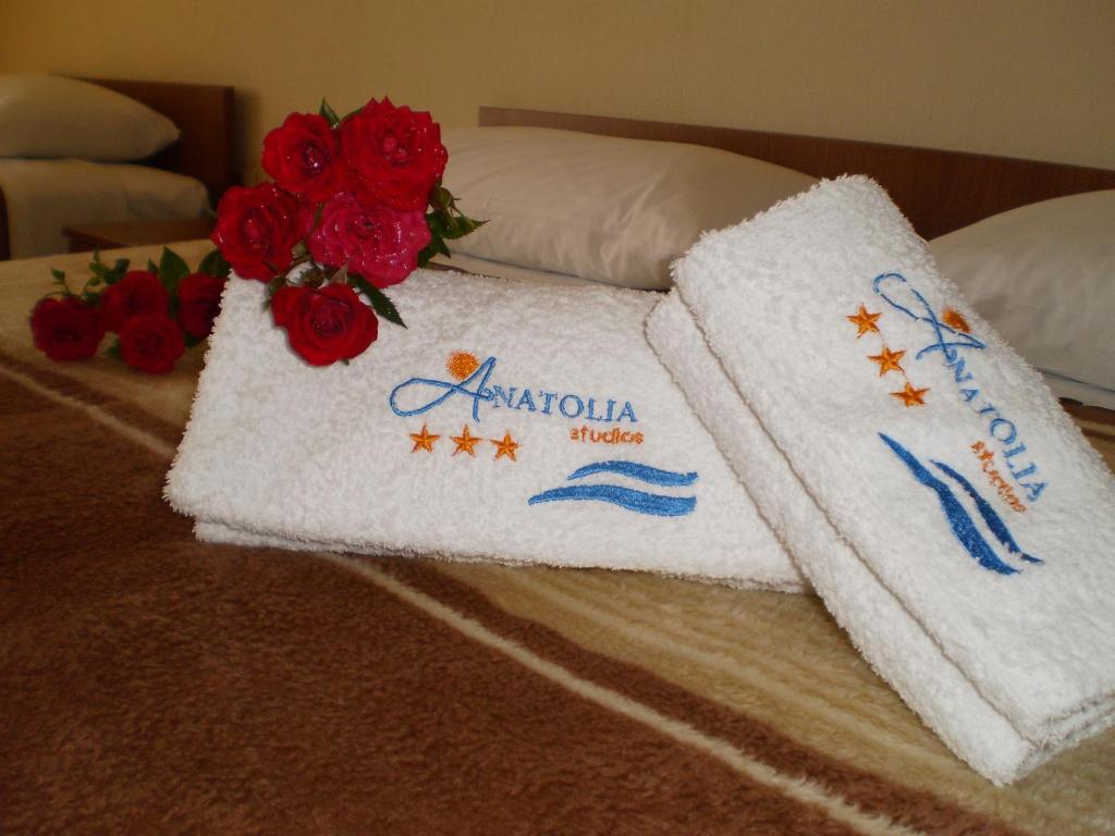 ein Paar Handtücher auf einem Bett mit roten Rosen in der Unterkunft Anatolia Studios in Kriopigi