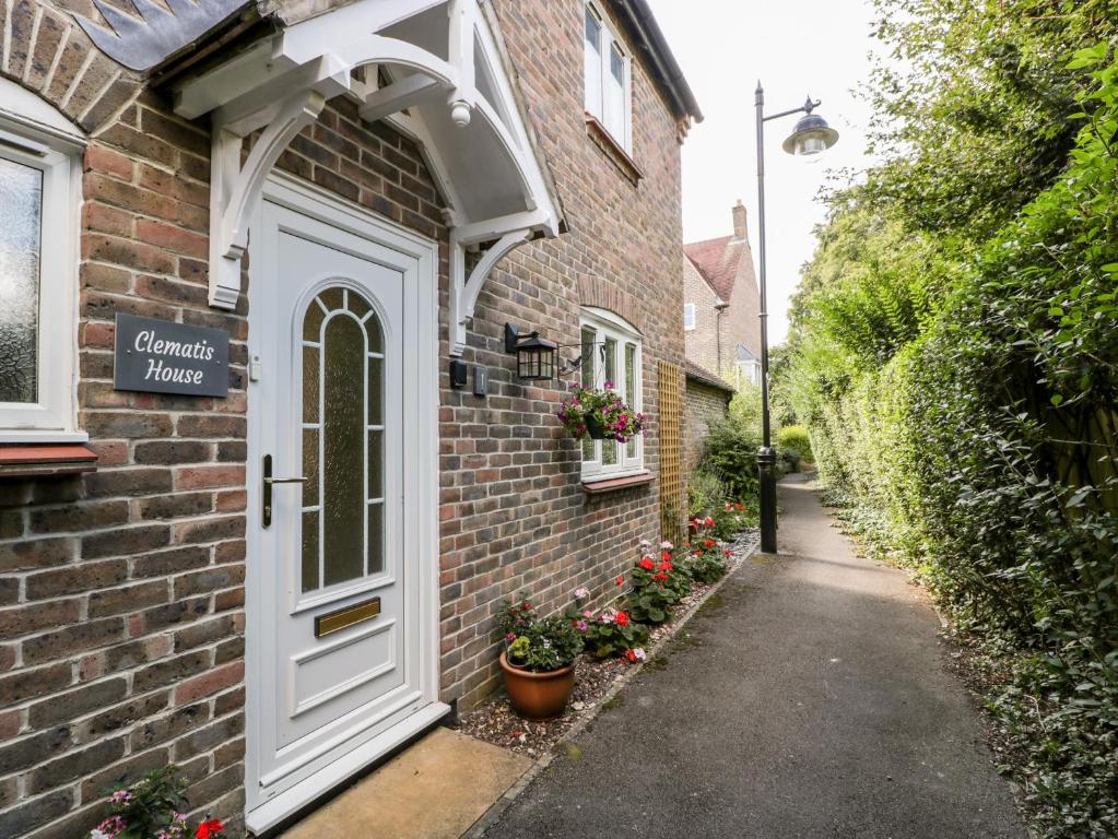 a brick house with a white door and flowers at Clematis House in Dorchester