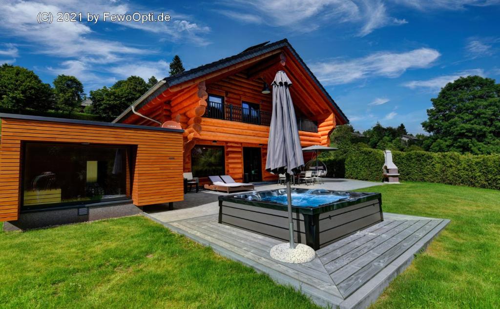 uma casa com piscina e guarda-sol em Ferienblockhäuser der Familie Lakmann em Feldberg