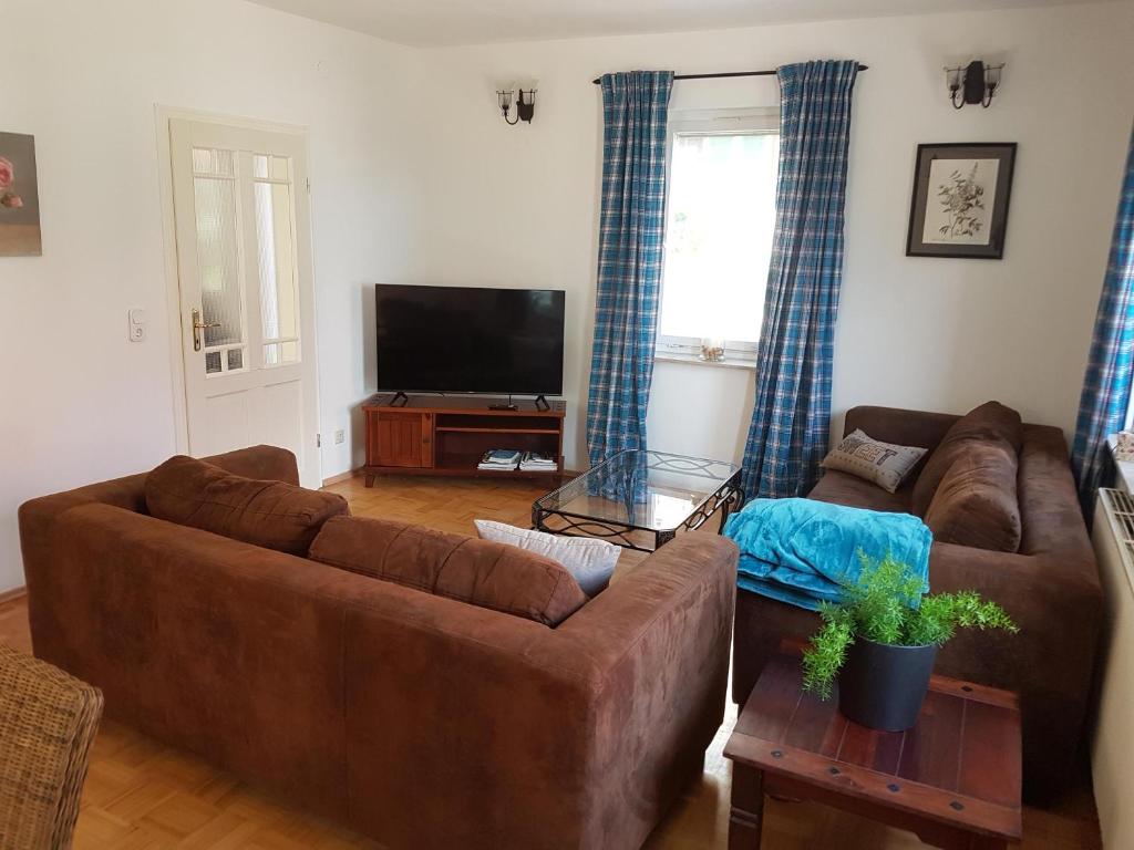 ein Wohnzimmer mit 2 braunen Sofas und einem Flachbild-TV in der Unterkunft Ferienhäusle vom Hof Chirphendorf 