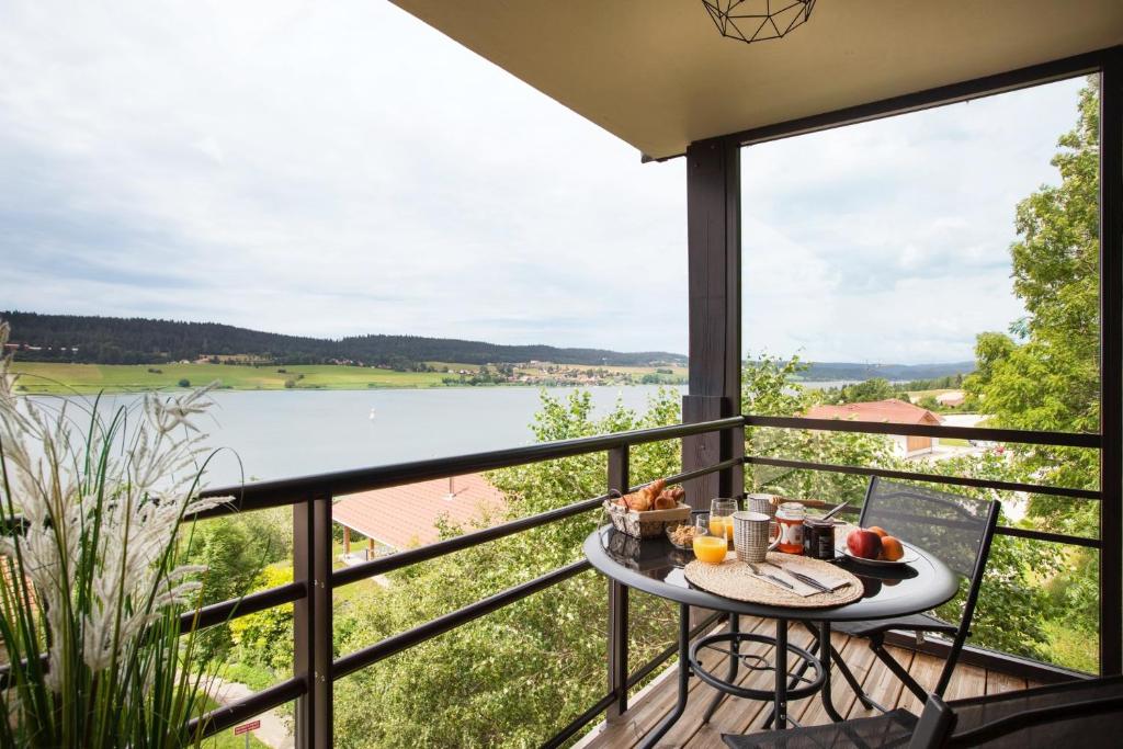 a table on a balcony with a view of a lake at Appartement Vue Lac in Malbuisson