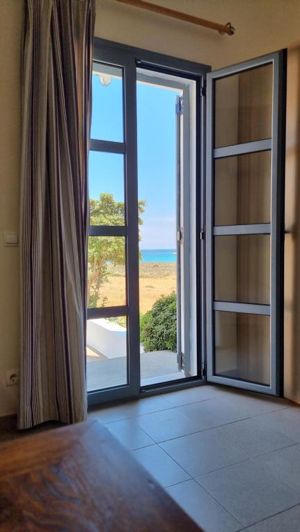 a room with a large glass door with a view of the ocean at Domatia me Thea in Elafonisos