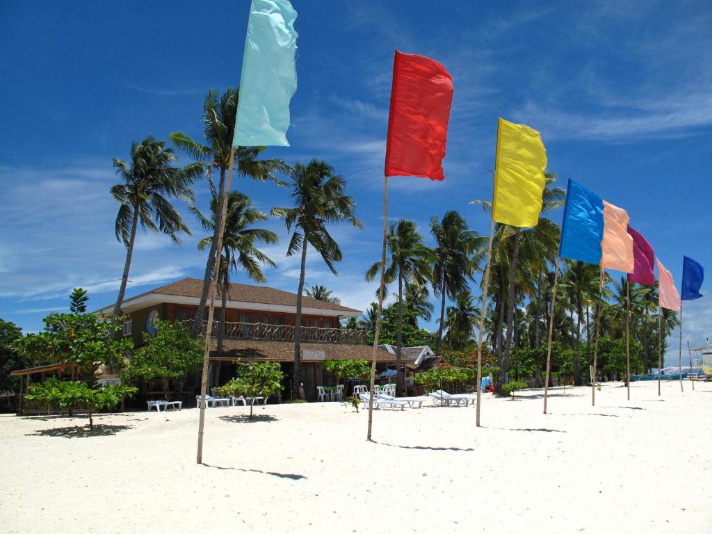 a row of flags on a beach with palm trees at Malapascua Legend Water Sports and Resort in Malapascua Island