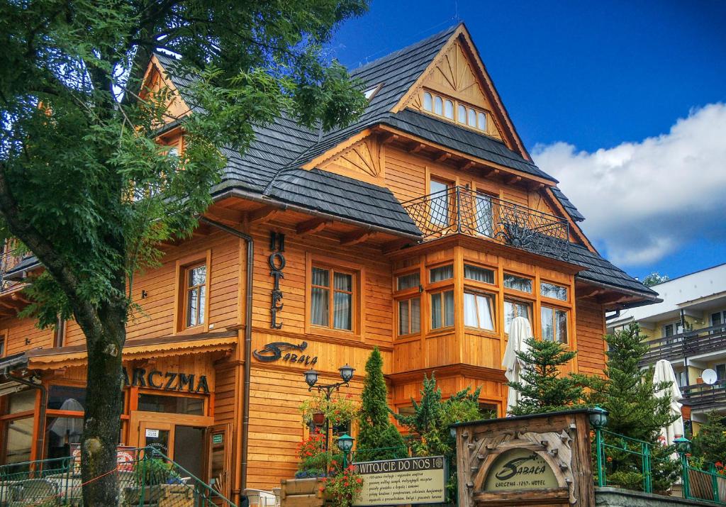 a large wooden house with a black roof at Hotel Sabała in Zakopane