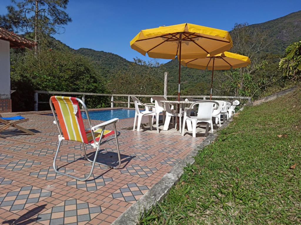 um pátio com uma mesa, cadeiras e um guarda-sol em Sitio Sao Jeronimo em Teresópolis