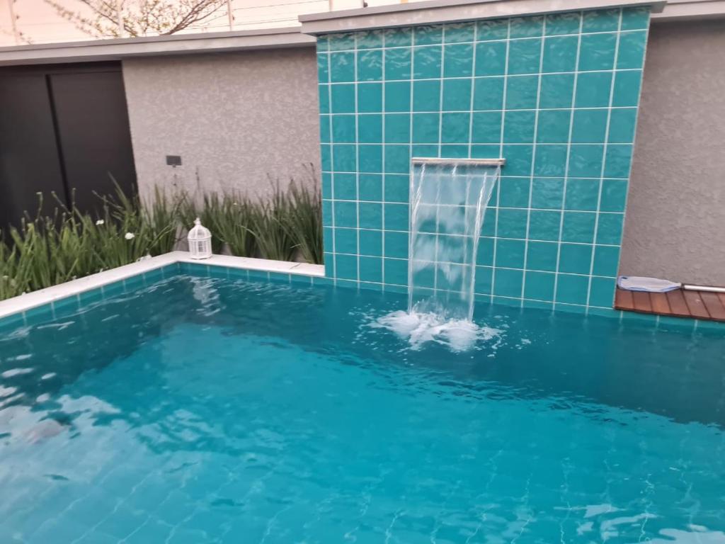 una piscina con una fuente de agua en una casa en Casa nova, conforto total e perto da praia, en Peruíbe