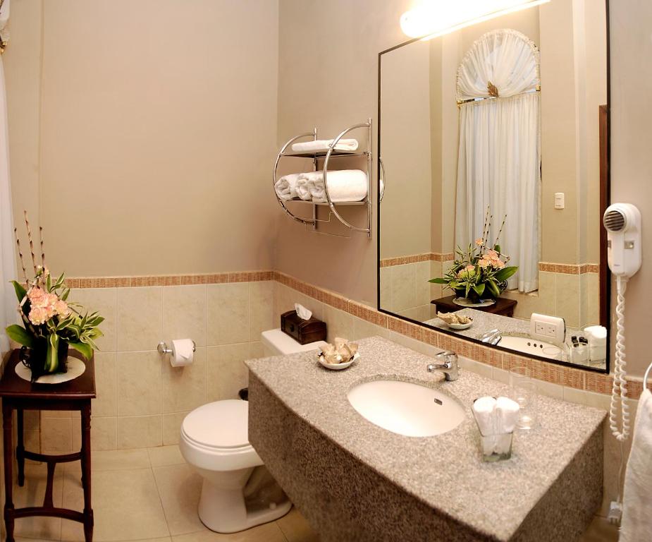 ein Badezimmer mit einem Waschbecken, einem WC und einem Spiegel in der Unterkunft Hotel Boutique Mansion Del Rio in Guayaquil