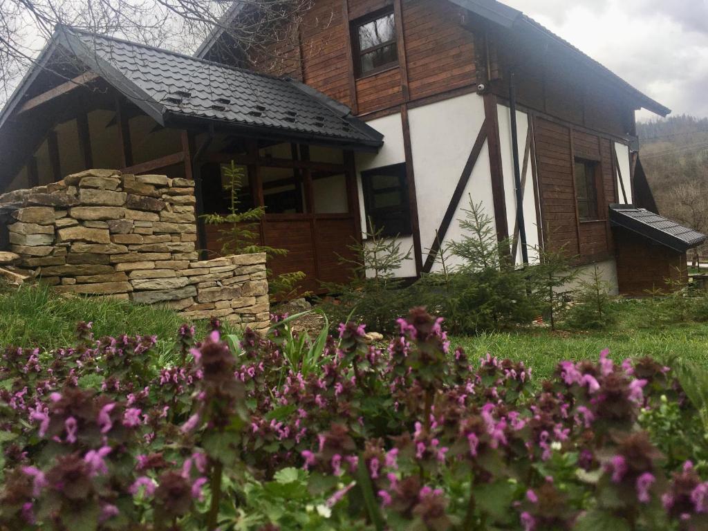 ein Blockhaus mit Blumen davor in der Unterkunft Шале Лаванда in Skole