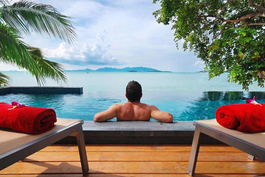 a man sitting in a pool looking out at the water at Villa Labaron in Koh Samui