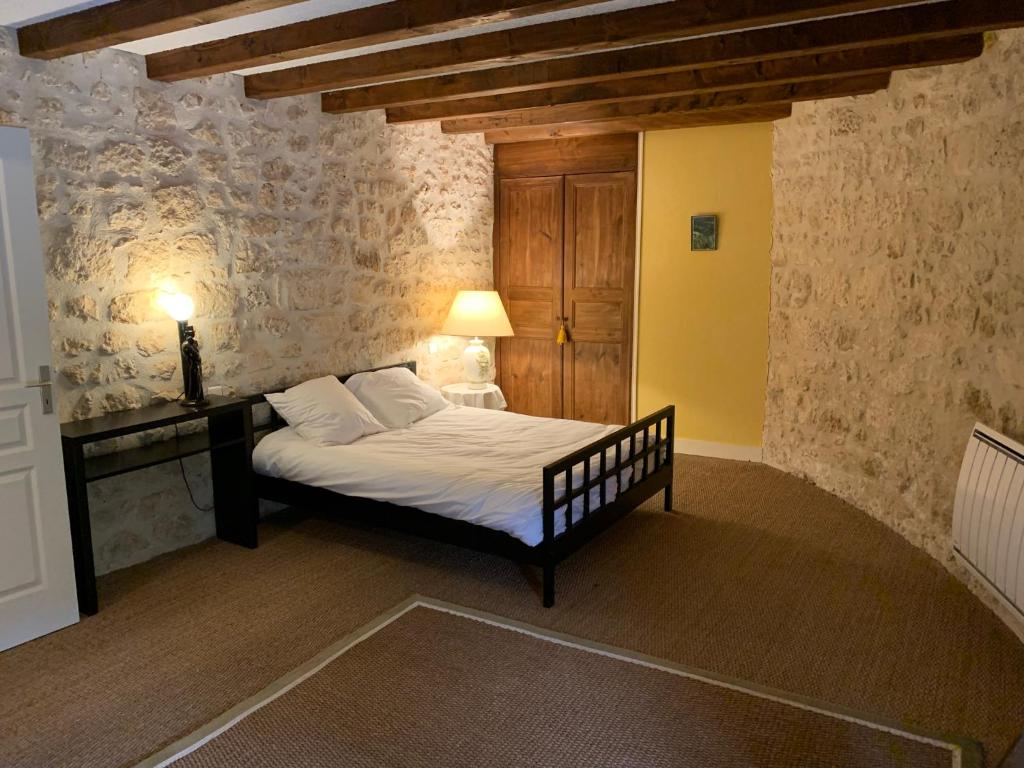 a bedroom with a bed in a room with a wall at Gite du moulin in Pranzac