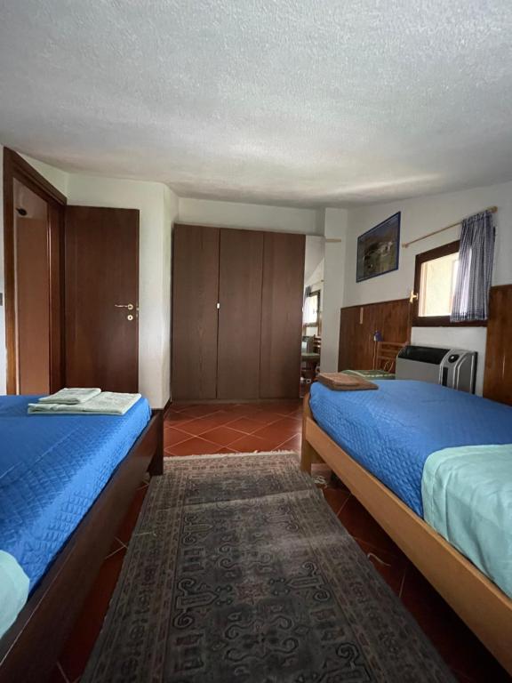 una camera d'albergo con due letti con lenzuola blu di Appartamento Fiore Rocca a Rocca di Mezzo